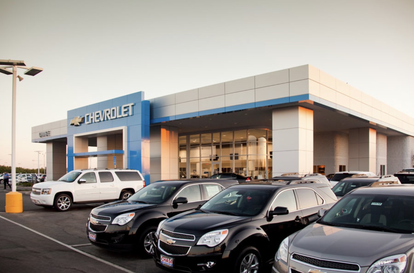 Dealership parking lot lined with vehicles, clean pavement.